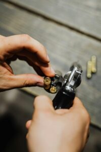 A detailed shot of hands loading bullets into a revolver on a wooden surface.